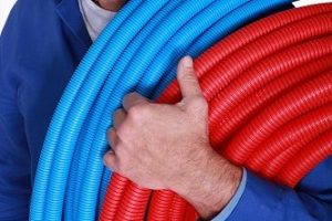 Electrician with rolls of blue and red corrugated plastic tubing
